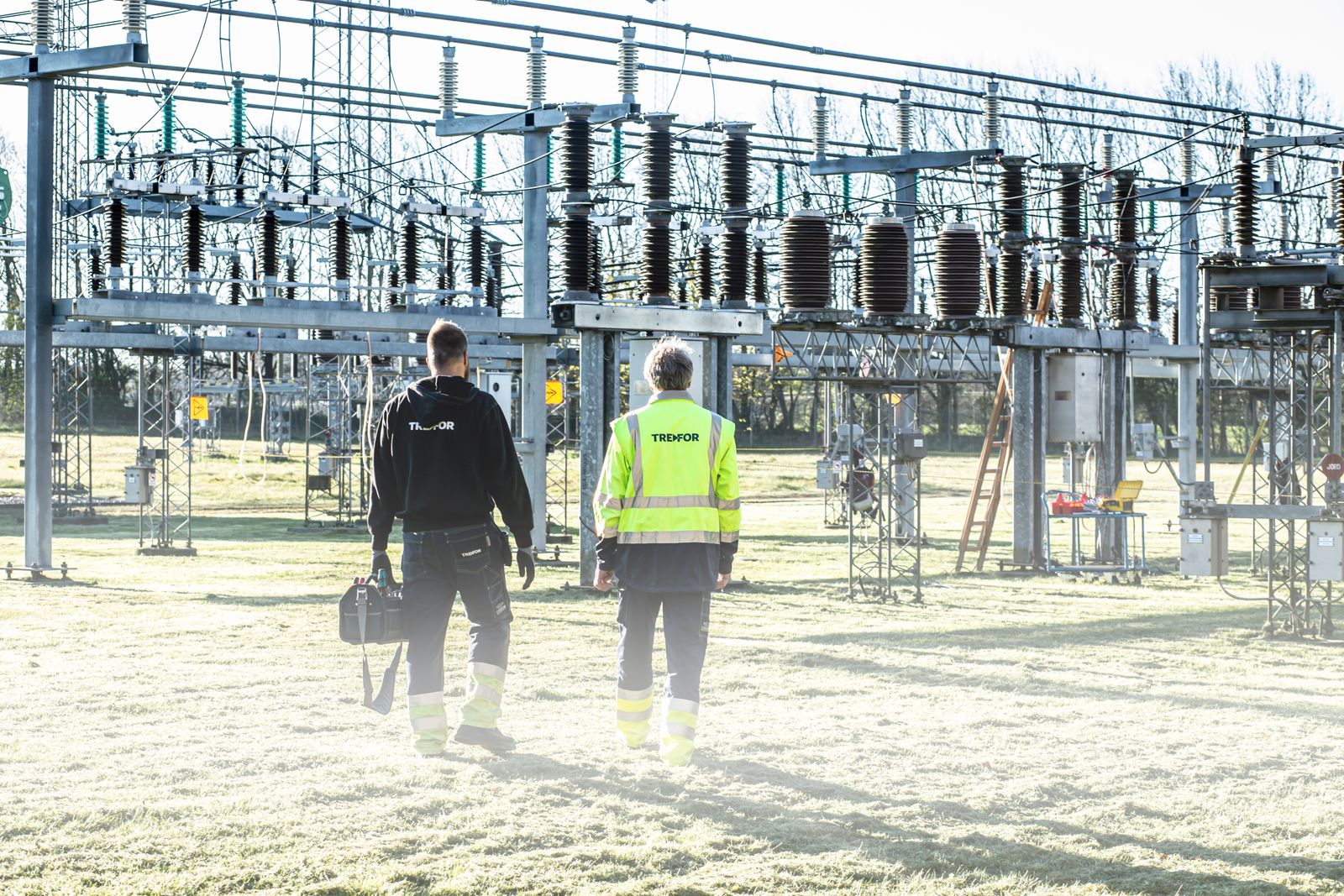 Two technicians walking toward high-voltage electrical equipment